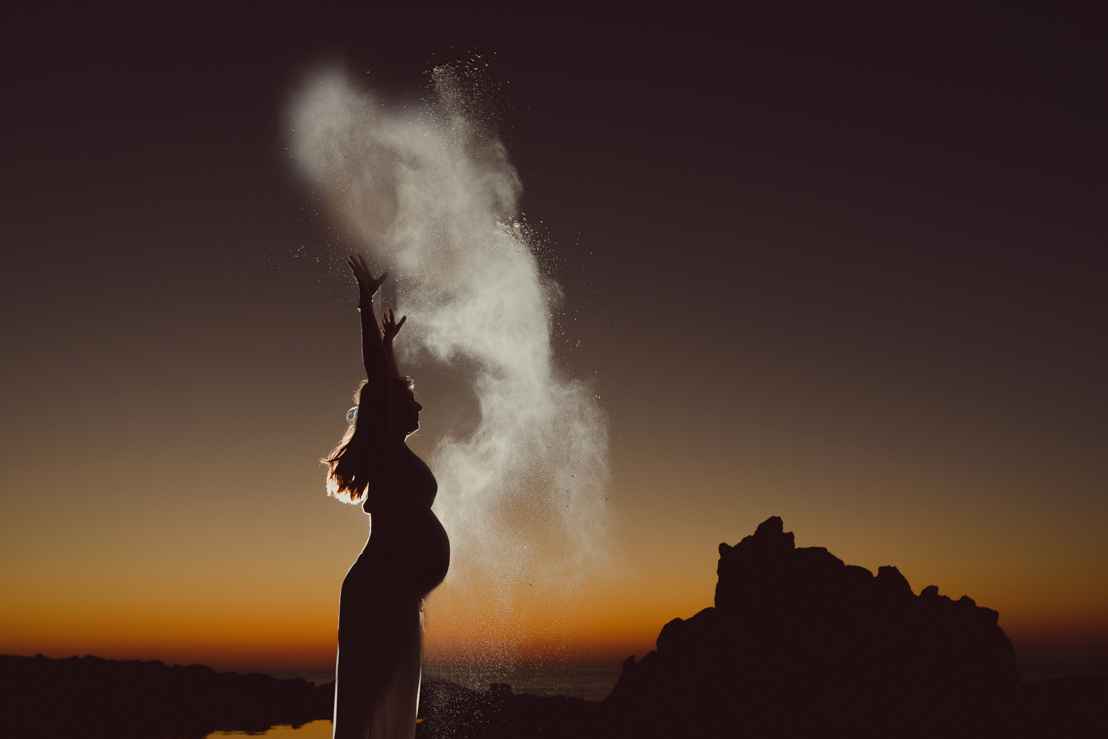 psicologia perinatal irun araceli vazquez - Araceli Vázquez Psicóloga en Irún Mujer embarazada en la playa al atardecer lanzando polvo al aire, simbolizando el empoderamiento y la conexión emocional en la psicología perinatal en Gabinete de Psicología Araceli Vázquez en Irún